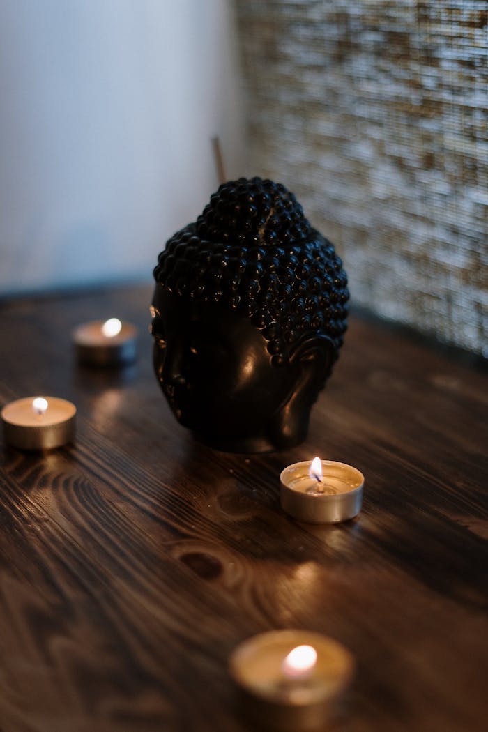 A serene setup with a Buddha head sculpture surrounded by soothing candlelight, perfect for relaxation.